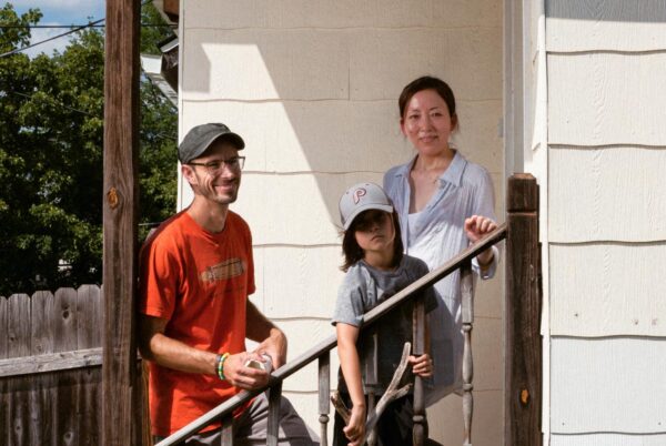 A mother and father smile on a staircase with their young son between them