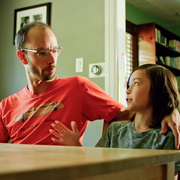 Dad and young daughter sitting at the kitchen table talking