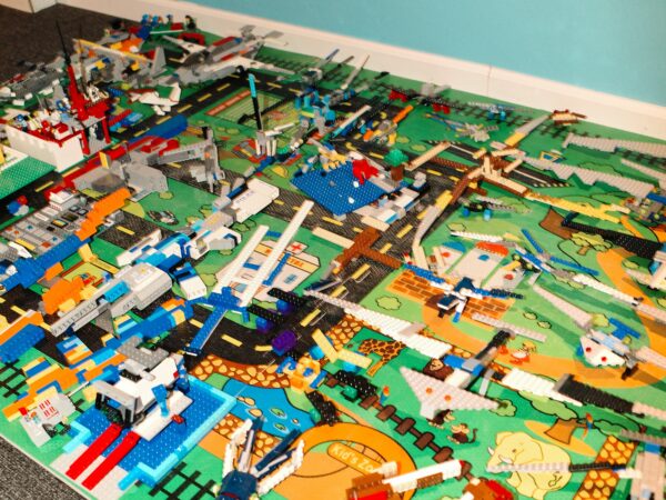 assortment of Lego in various states of assembly on a child's play rug