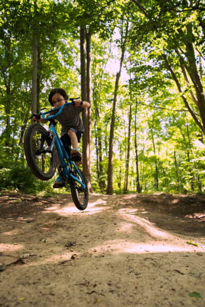 Young person jumping a mountain bike in the forest