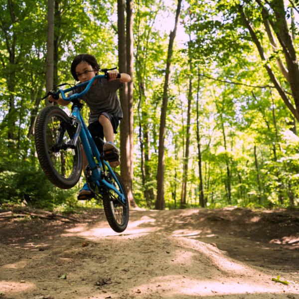 Young person jumping a mountain bike in the forest