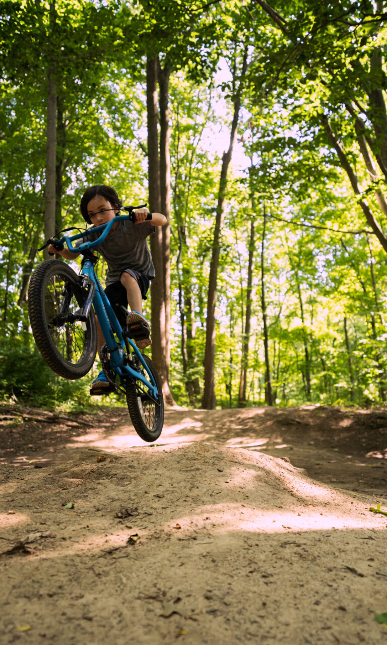 Young person jumping a mountain bike in the forest