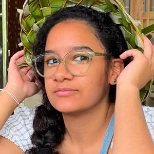 Photo of Analê Fernandez looking off-camera and adjusting her glasses.