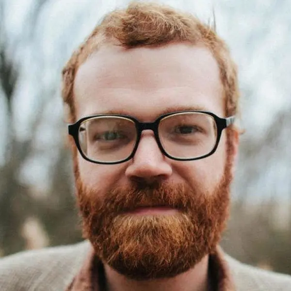 Headshot of Caleb Colier in glasses with a beard.