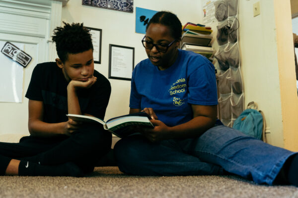 A woman and a child on the floor reading a book.