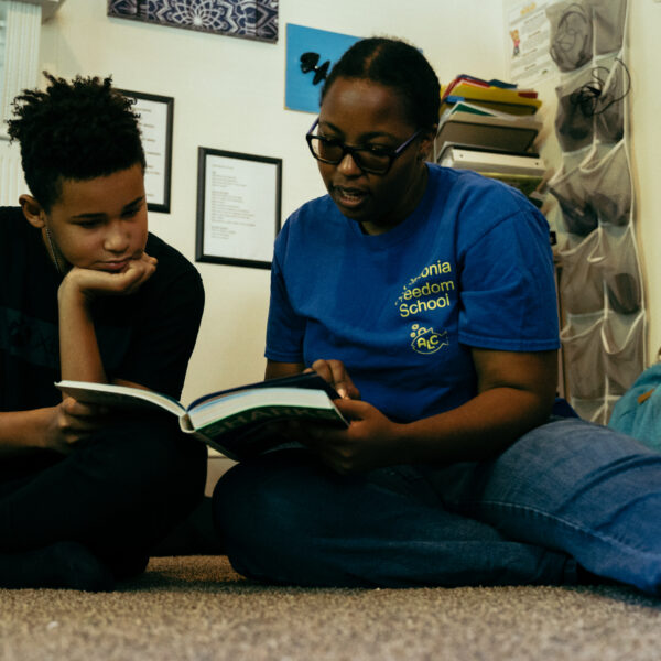 A woman and a child on the floor reading a book.