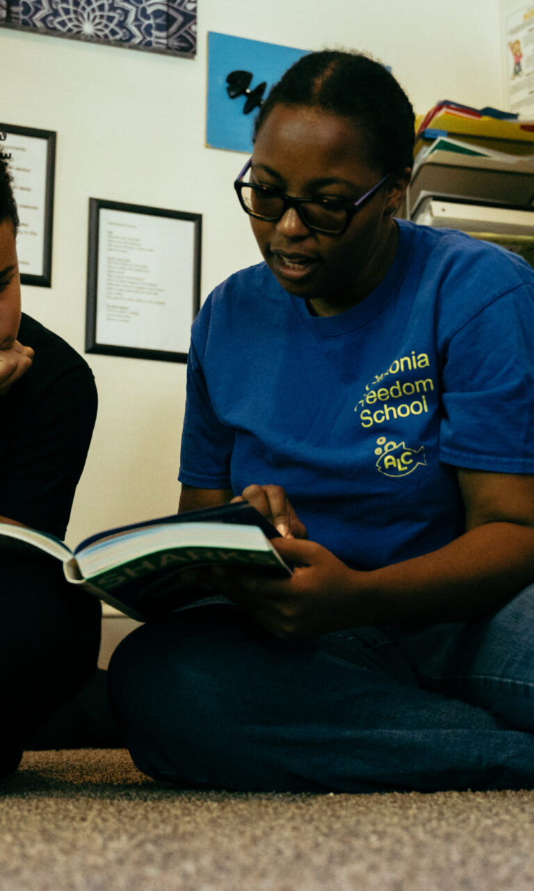 A woman and a child on the floor reading a book.