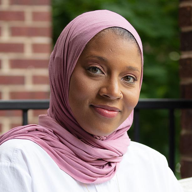 Ashley Marshall-Seward smiles at the camera. A Black woman wearing a pink hijab