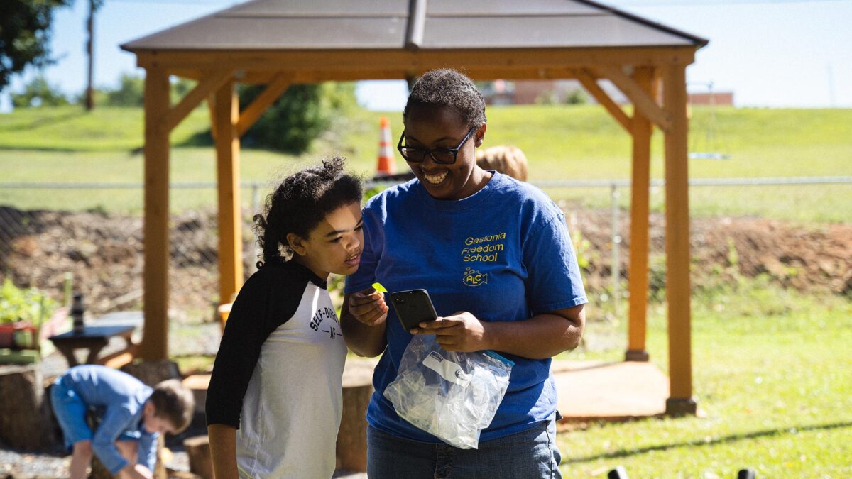 A Black woman and her young daughter smile at a cell phone