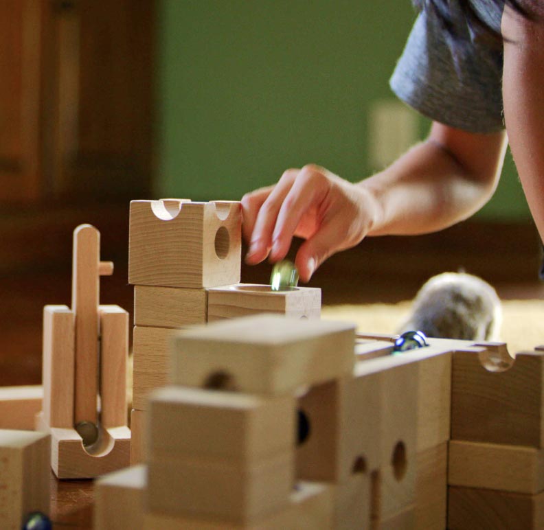 A closeup photo of Kai's hands playing with wooden blocks