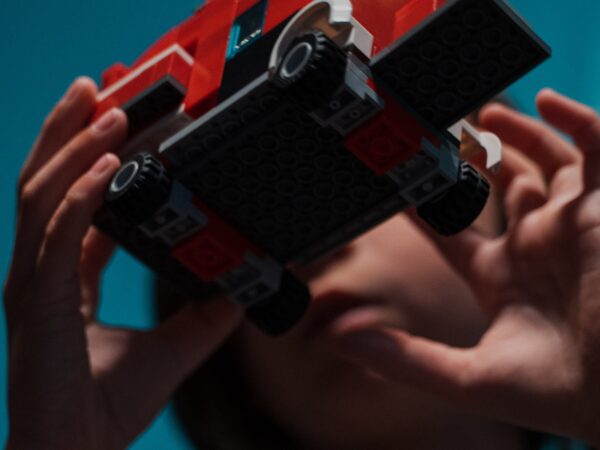 A close up of a young boy, Kai, playing with a truck made of Legos in front of his face.