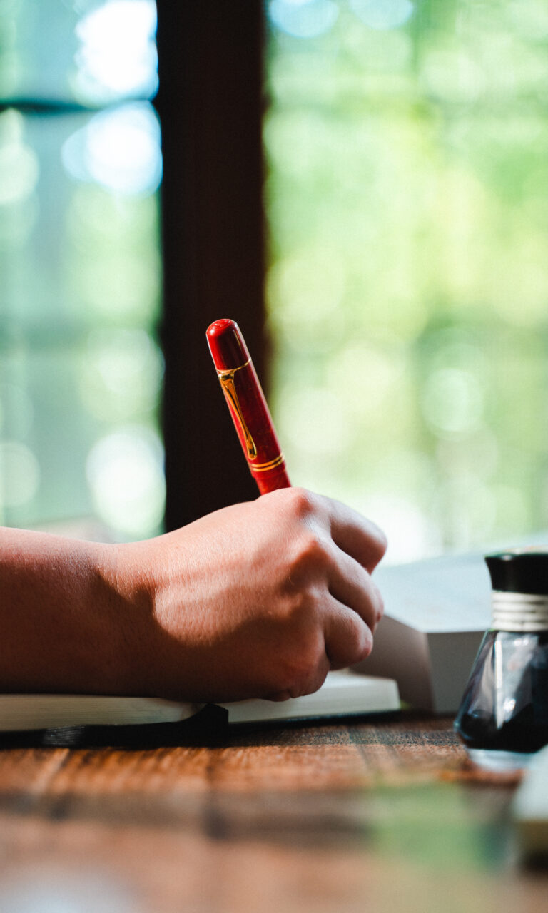 A closeup of a woman's hand holding a pen and writing.