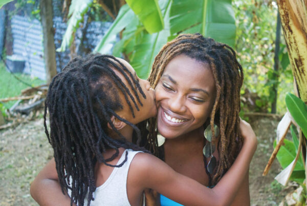 A daughter kissing her mother on the cheek as they embrace in a hug.
