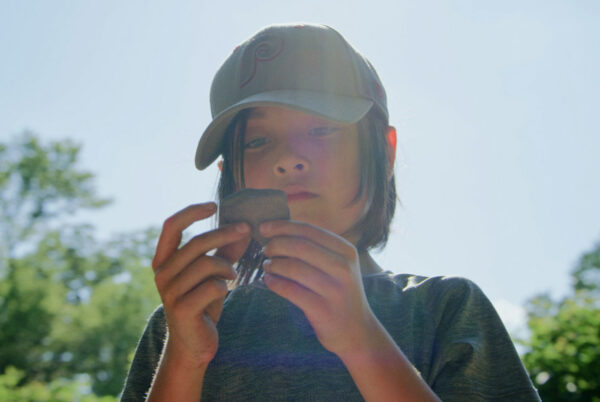 Young person outdoors examining a rock