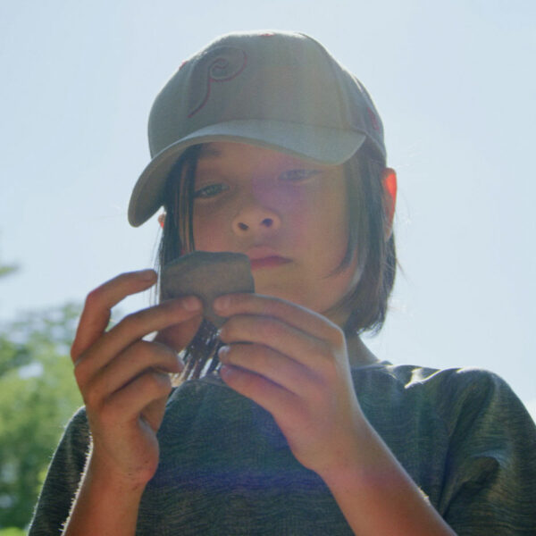 Young person outdoors examining a rock