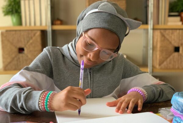 Tween girl draws with a crayon and smiles