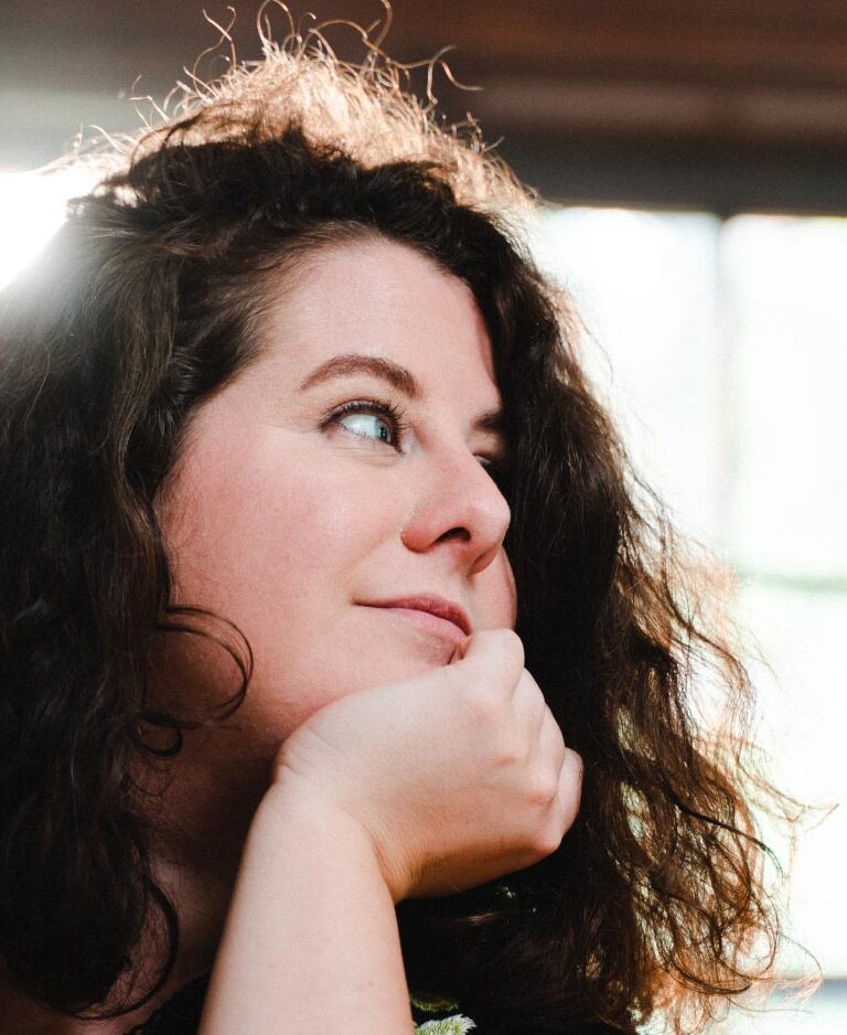 A closeup image of Annie Westphal, backlit by a sunny window.