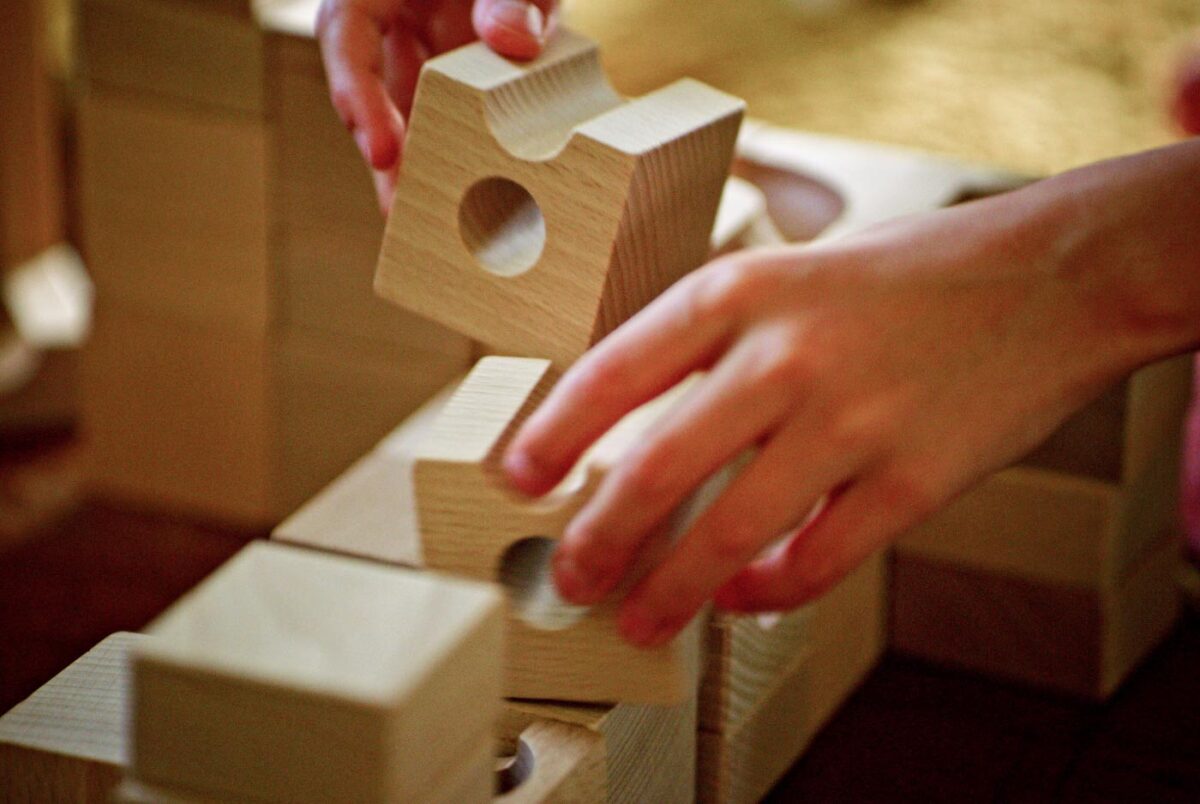 A kid's hands blaying with big wooden blocks.
