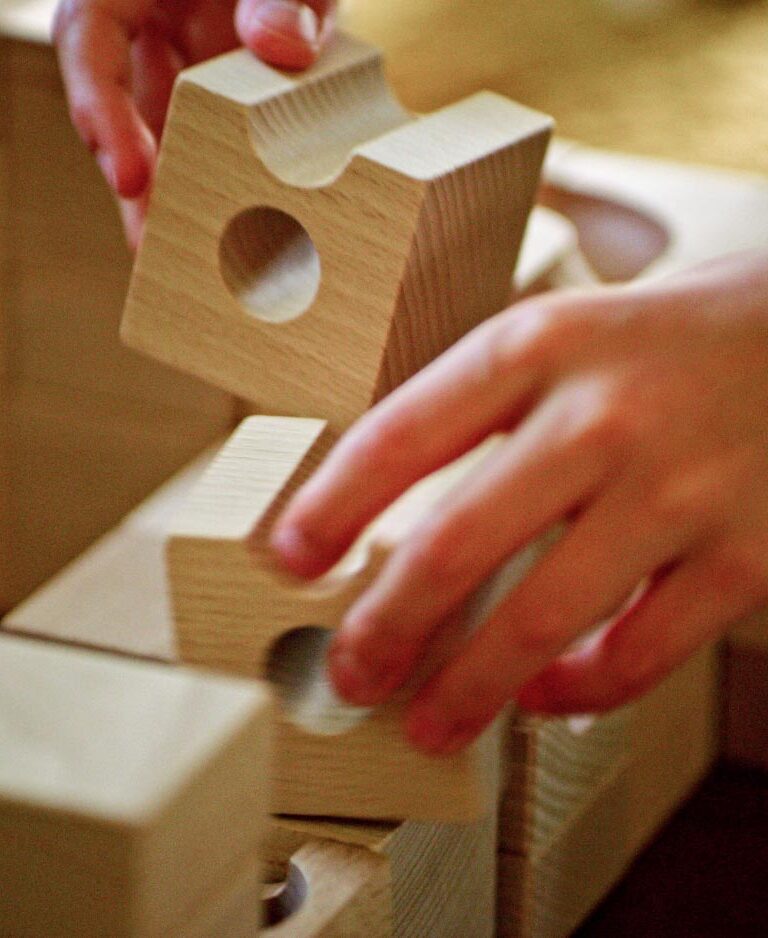 A kid's hands blaying with big wooden blocks.