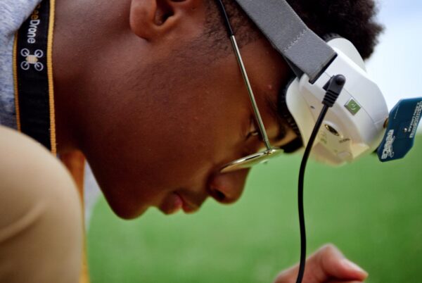 A closeup of Ashley's son Yusef looking at something out of frame in his hands with googles resting on his forehead.