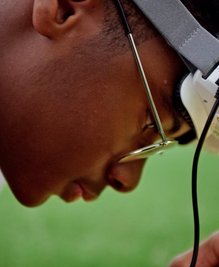 A closeup of Ashley's son Yusef looking at something out of frame in his hands with googles resting on his forehead.