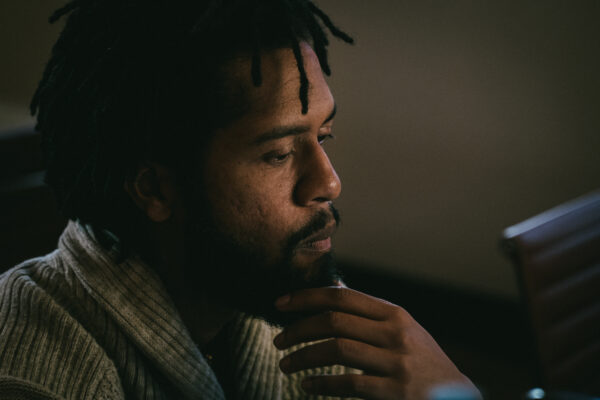 A man with his hand on his chin, contemplating something off-camera.