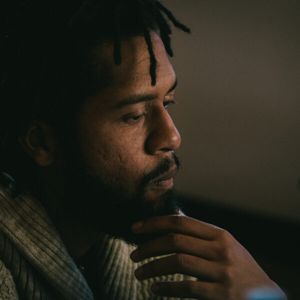 A man with his hand on his chin, contemplating something off-camera.