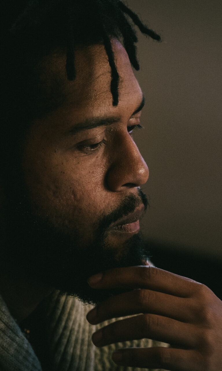 A man with his hand on his chin, contemplating something off-camera.