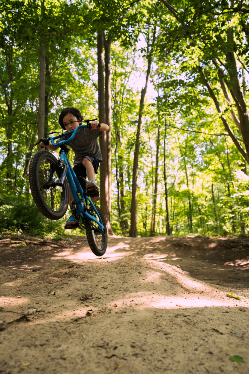 Young person jumping a mountain bike in the forest