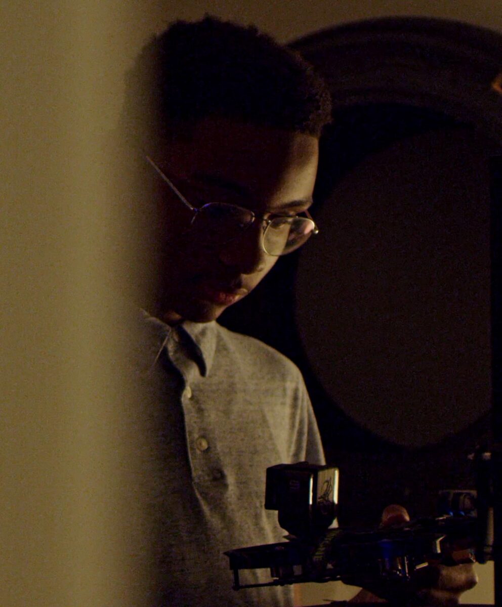 A teenage Black boy looks at a drone remote