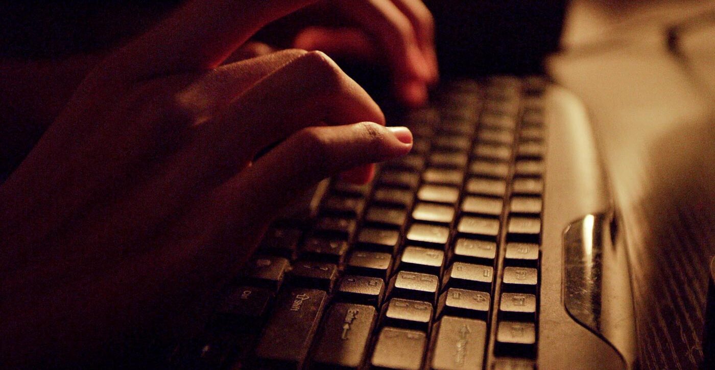 Black teenage boy's hands type on a keyboard